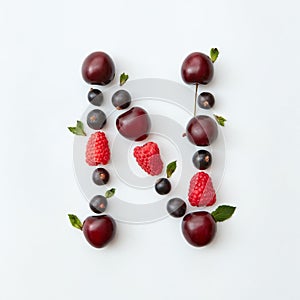 Fruits pattern of letter N english alphabet from natural ripe berries - black currant, cherries, raspberry, mint leaf