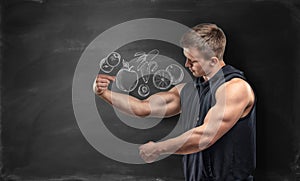 Fruits pictured on black background and fitness man showing his bicep under the picture