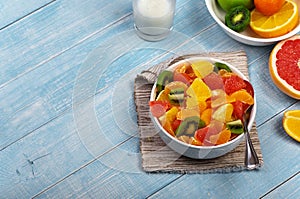 Fruits salad in plate on blue wooden table closeup