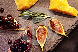 Fruits and slices of hard cheese on a background of dark stone countertops. Still life of healthy products. Close-up