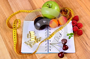 Fruits, tablets supplements and centimeter with notebook, slimming and healthy food