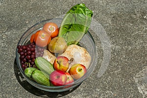 Fruits and vegetables in bowl on cement background