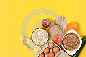 Fruits, vegetables, cereals, bread, noodles and a bottle of water on a yellow background copy space
