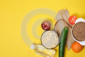 Fruits, vegetables, cereals, bread, noodles and a bottle of water on a yellow background copy space