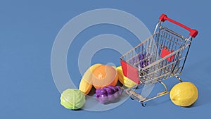 Fruits and vegetables on the floor around an empty shopping cart