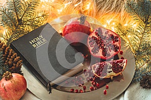 Fruits and vegetables for harvesting. Still life - bible and pomegranate on an iron plate in the branches of the Christmas tree