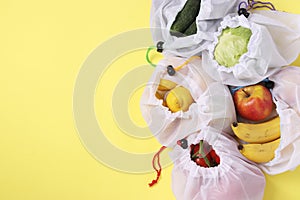 Fruits and vegetables in reusable eco friendly mesh bags on bright yellow background. Space for text, Zero waste concept