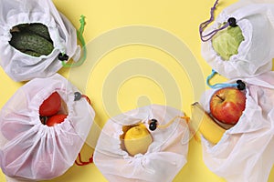 Fruits and vegetables in reusable eco friendly mesh bags on bright yellow background. Space for text, Zero waste concept