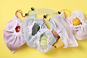 Fruits and vegetables in reusable eco friendly mesh bags on bright yellow background, Zero waste concept. Stop pollution