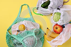 Fruits and vegetables in reusable eco friendly mesh bags on bright yellow background. Zero waste concept. Top view