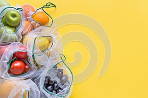 Fruits and vegetables in reusable eco-friendly mesh bags on bright yellow background. Zero waste shopping. Ecological concept.