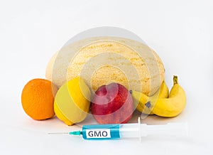 Fruits on a white background bananas, orange, melon, lemon and nectarine, next is a syringe with gmo and nitrates