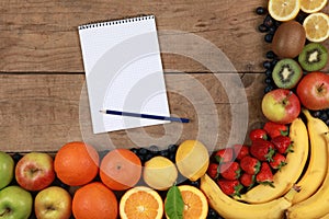 Fruits on a wooden board with notebook