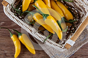 Fruits of yellow fresh chilli pepper in the basket on a wooden b