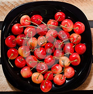 Fruits yellow and red cherry in form of heart on a black plate