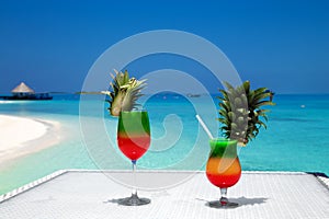 fruity cocktail on a beach table. Maldives Island landscape. Tropical fresh juices on white sandy beach. Colorful fruity