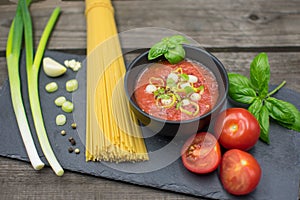 fruity tomato sauce in a bowl decorated with spring onions and basil.