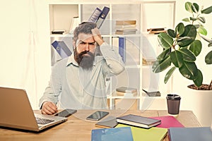 Frustated professional guy clutching head working at office desk, frustration