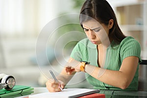 Frustated student checking smartwatch at home