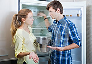 Frustraited starving female and man near fridge without any food