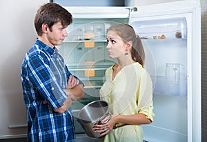 Frustraited starving female and man near fridge without any food