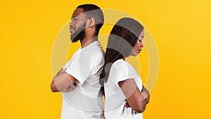 Black couple standing back to back, yellow studio wall