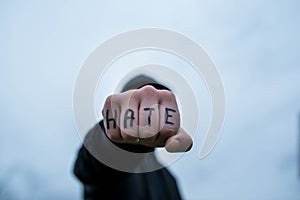 Frustrated , aggressive teenage boy showing hes fist with the word hate