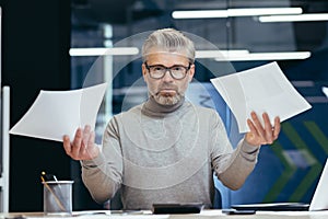 Frustrated and angry businessman with documents, mature gray businessman checking financial reports, boss not satisfied