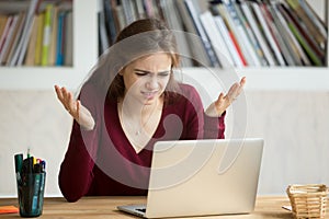 Frustrated annoyed woman confused by computer problem looking at