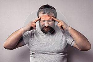 Frustrated bearded man touching his head with hands and keeping eyes closed