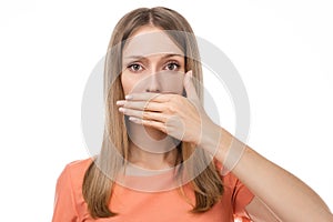 Frustrated blond girl is covering mouth with hand not willing to disclose something important. Keep a secret