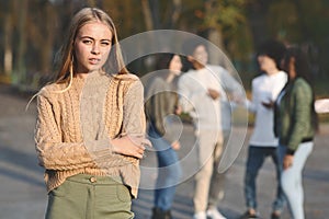 Frustrated blondy girl standing over group of teenagers