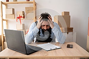 Frustrated business man looking at laptop holding his hands to head in frustration. portrait of tired sick upset young