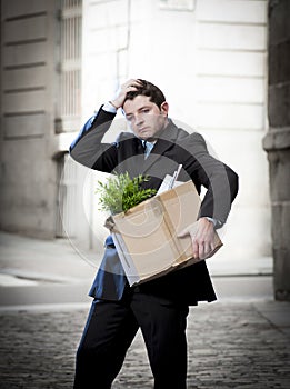 Frustrated business man on street fired carrying cardboard box