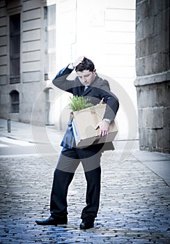 Frustrated business man on street fired carrying cardboard box