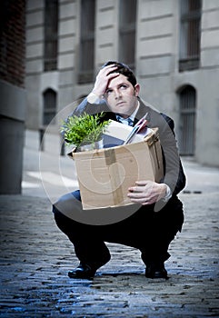 Frustrated business man on street fired carrying cardboard box