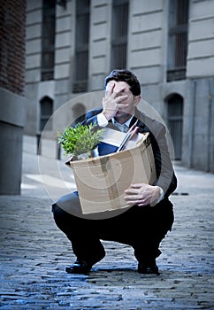 Frustrated business man on street fired carrying cardboard box