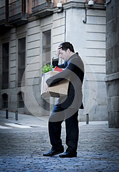 Frustrated business man on street fired carrying cardboard box