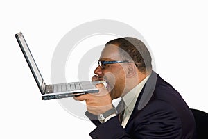 Frustrated businessman biting into his laptop