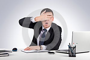 Frustrated businessman close his eyes by hand on gray background