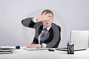 Frustrated businessman close his eyes by hand on gray background