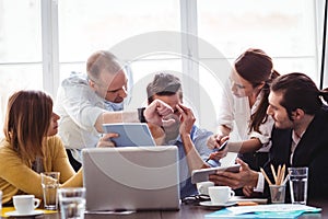 Frustrated businessman in between coworkers showing technologies