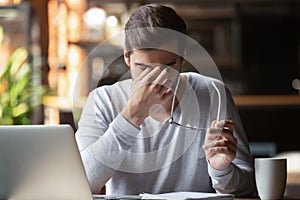 Frustrated businessman holding glasses feel eye strain, computer syndrome