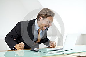 Frustrated businessman shouting at laptop