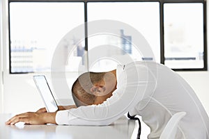 Frustrated Businessman Sitting At Desk In Office Using Laptop