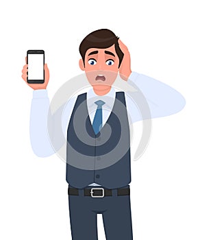 Frustrated businessman in vest suit showing mobile, cell or smartphone. Shocked trendy person holding hand on head. Male character