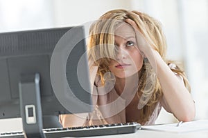 Frustrated Businesswoman With Hands In Hair At Office Desk