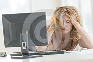 Frustrated Businesswoman With Hands In Hair Sitting At Desk