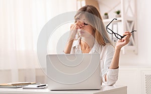 Frustrated Businesswoman Massaging Nosebridge Sitting At Workplace
