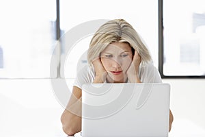 Frustrated Businesswoman Sitting At Desk In Office Using Laptop